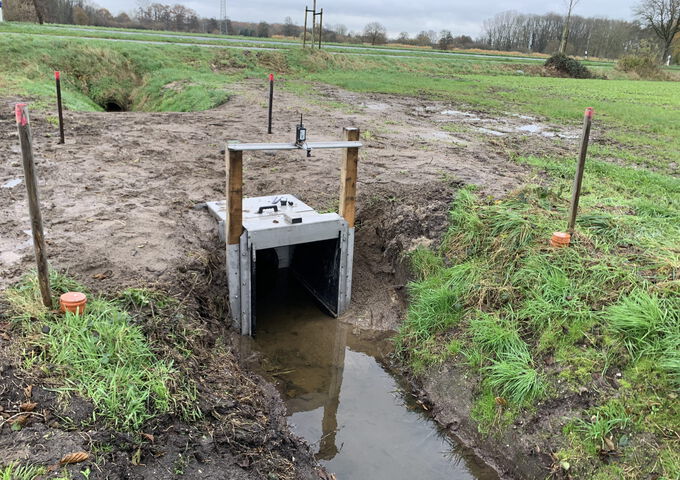 Steuerbauwerk zur Wasserstandsteuerung in einem Graben zwischen begrünten Flächen als Teil des Projekts NiersCon.